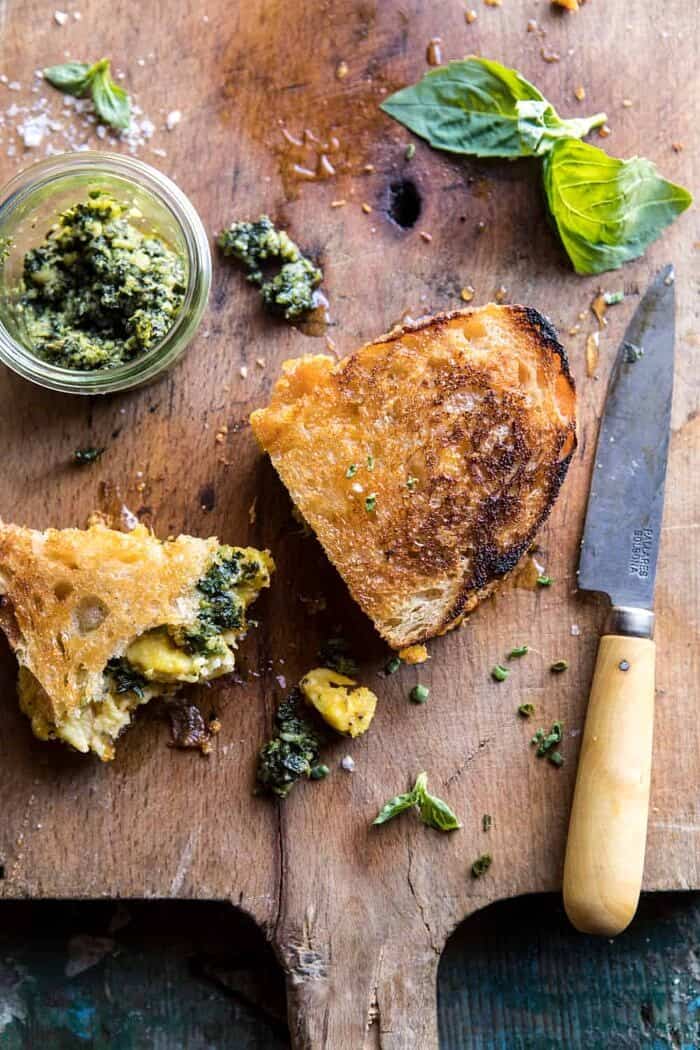 over photo of half eaten Breakfast Grilled Cheese with Soft Scrambled Eggs and Pesto