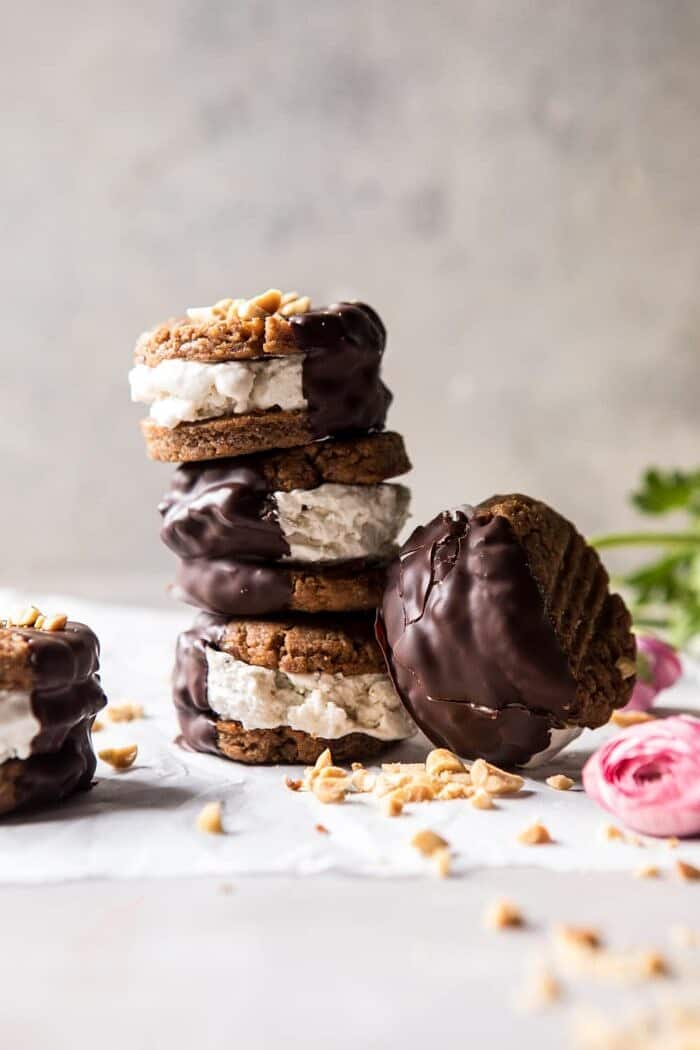 front on stacked photo of Chocolate Dipped Peanut Cookie Ice Cream Sandwiches with extra cookie resting on the side of stack