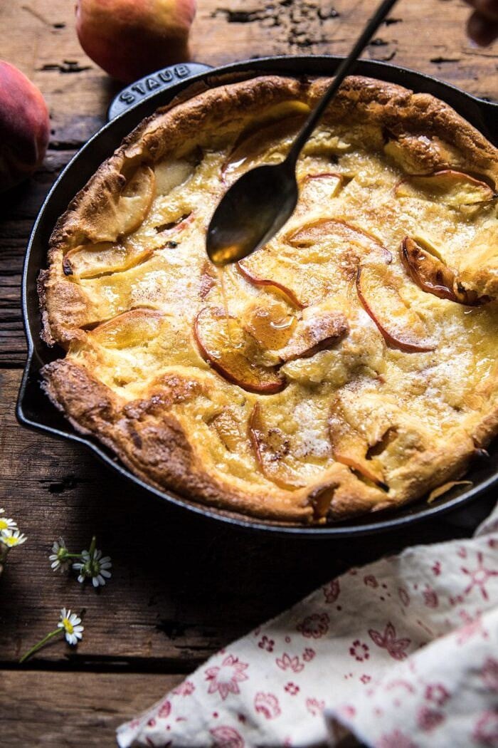 drizzling maple syrup on Browned Butter Cinnamon Peach Dutch Baby 