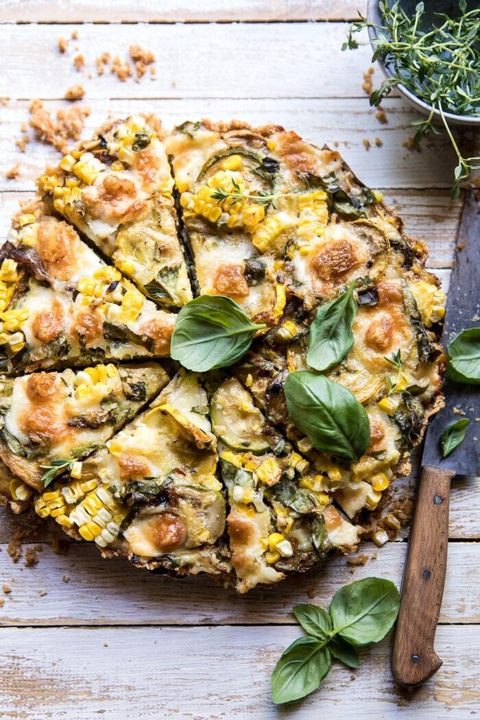 overhead photo of Cheesy Zucchini and Corn Pie with 4 pieces cut and a knife