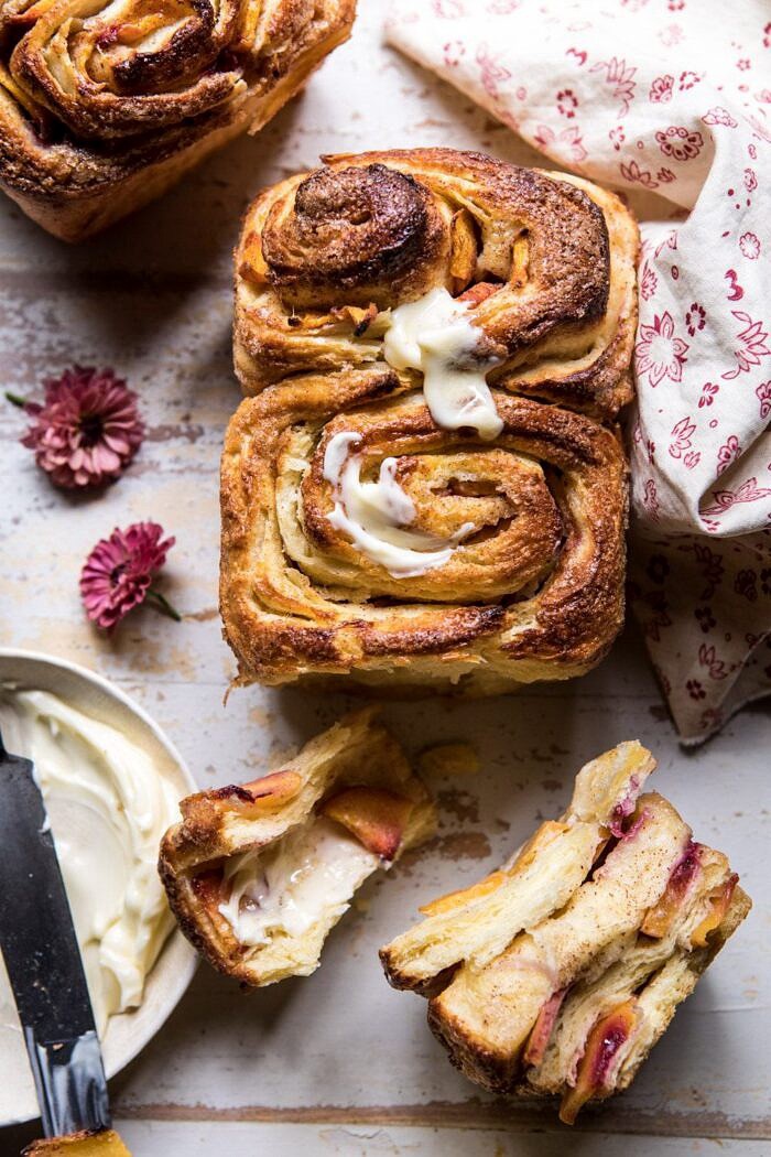 overhead photo of Flaky Pull Apart Cinnamon Peach Brioche Bread with butter and flowers in photo