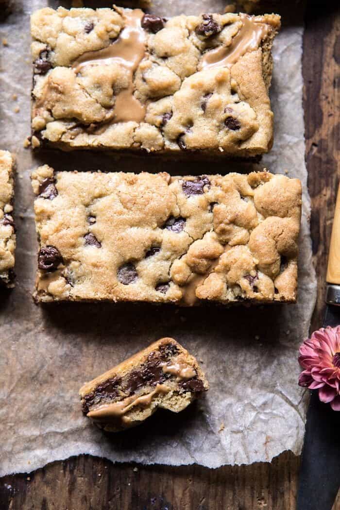 close up photo of Chocolate Chip Peanut Butter Swirled Cookie Bars with flower and knife in photo 
