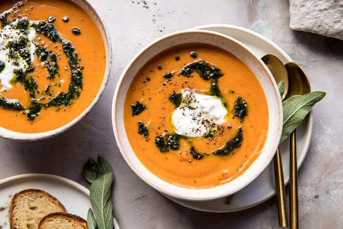 horizontal photo of Golden Sweet Potato Soup with Burrata and Sage Pesto with bread on table