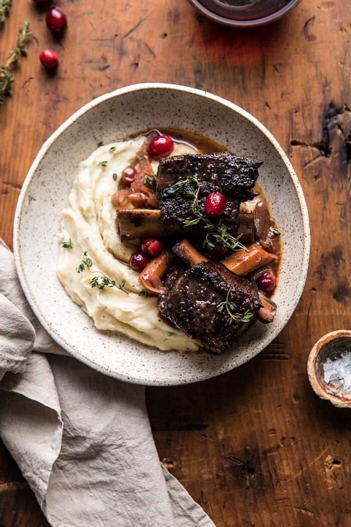 overhead photo of Red Wine Cranberry Braised Short Ribs with mashed potatoes, wine and salt in photo 