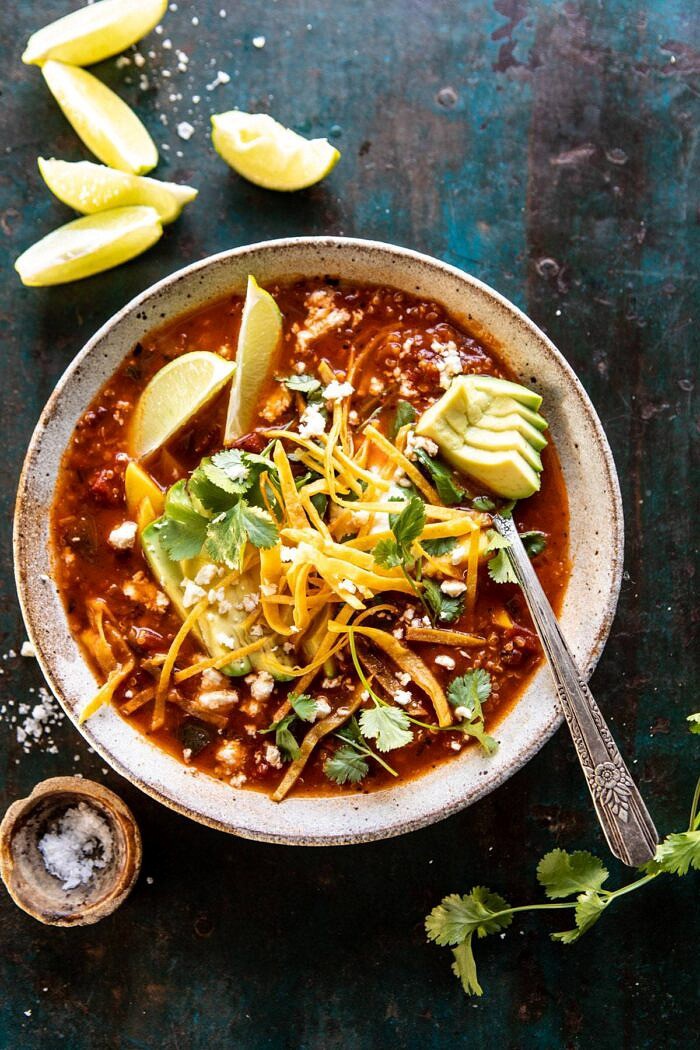 overhead photo of Crockpot Spicy Vegetarian Tortilla Soup with Quinoa with spoon in bowl and limes on table