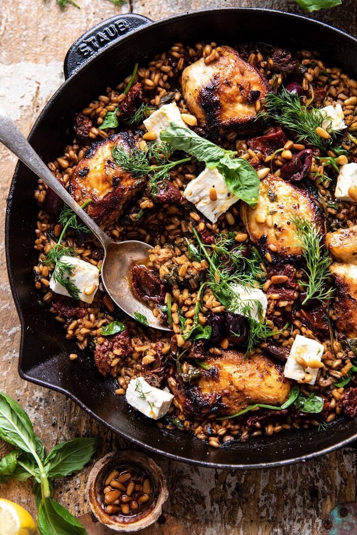 overhead close up photo of One Skillet Greek Sun-Dried Tomato Chicken and Farro with spoon in skillet 