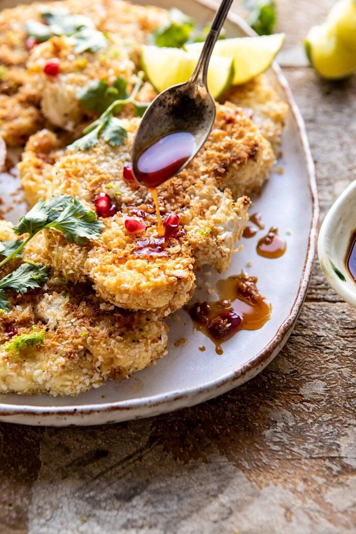 side angle photo Sesame Crusted Cauliflower with Pomegranate Ponzu Sauce being drizzled on cauliflower 