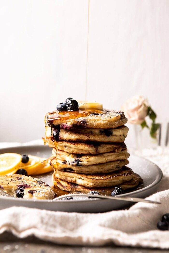 side angled photo Blueberry Lemon Ricotta Pancakes with syrup being drizzle on
