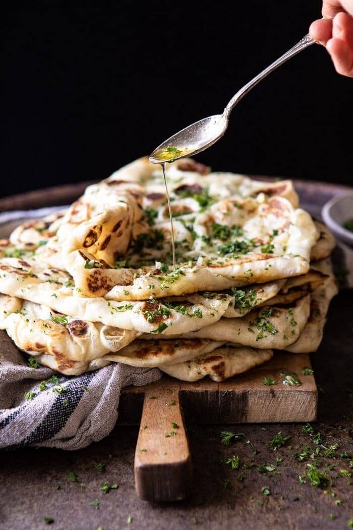 side angle photo of drizzling butter over Herbed Garlic Butter Naan 