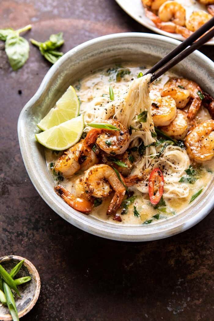 side angled photo of Saucy Garlic Butter Shrimp with Coconut Milk and Rice Noodles being pulled up out of the bowl with chopsticks
