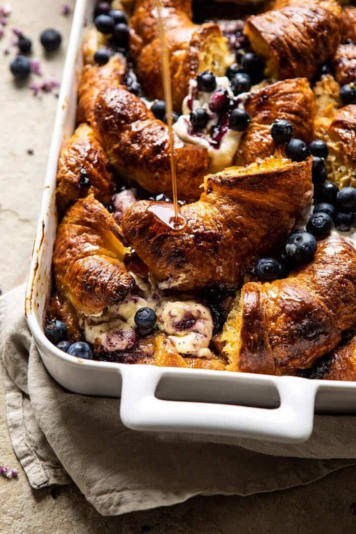 side angled photo of Berry and Cream Cheese Croissant French Toast Bake with maple being drizzled on top 