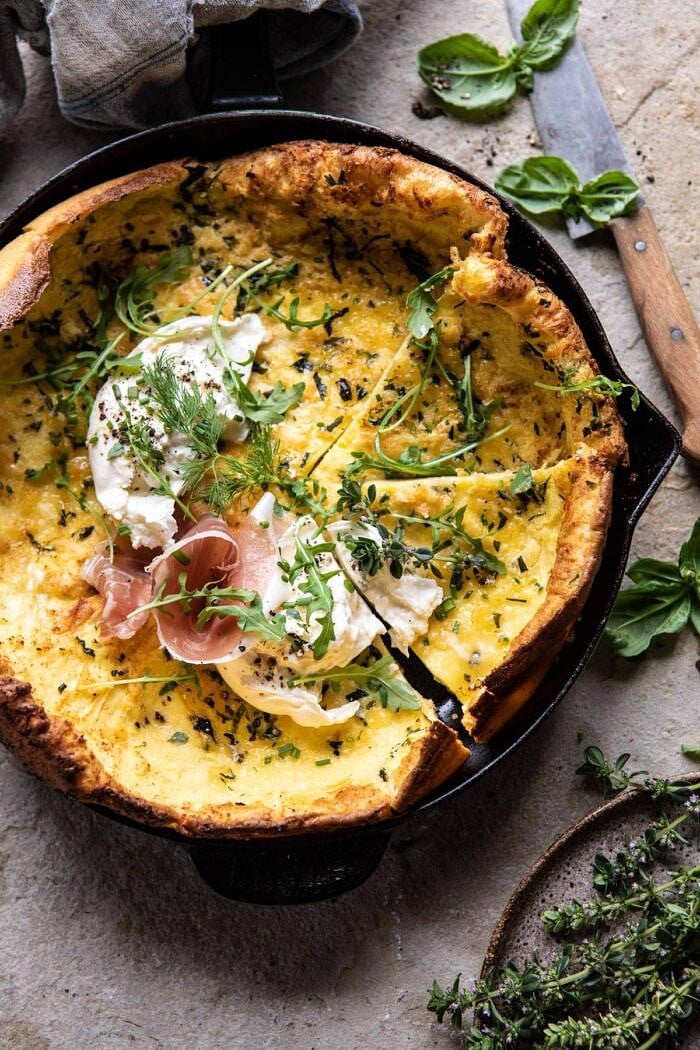 over photo of Savory Herb Butter Dutch Baby in skillet with 3 pieces cut