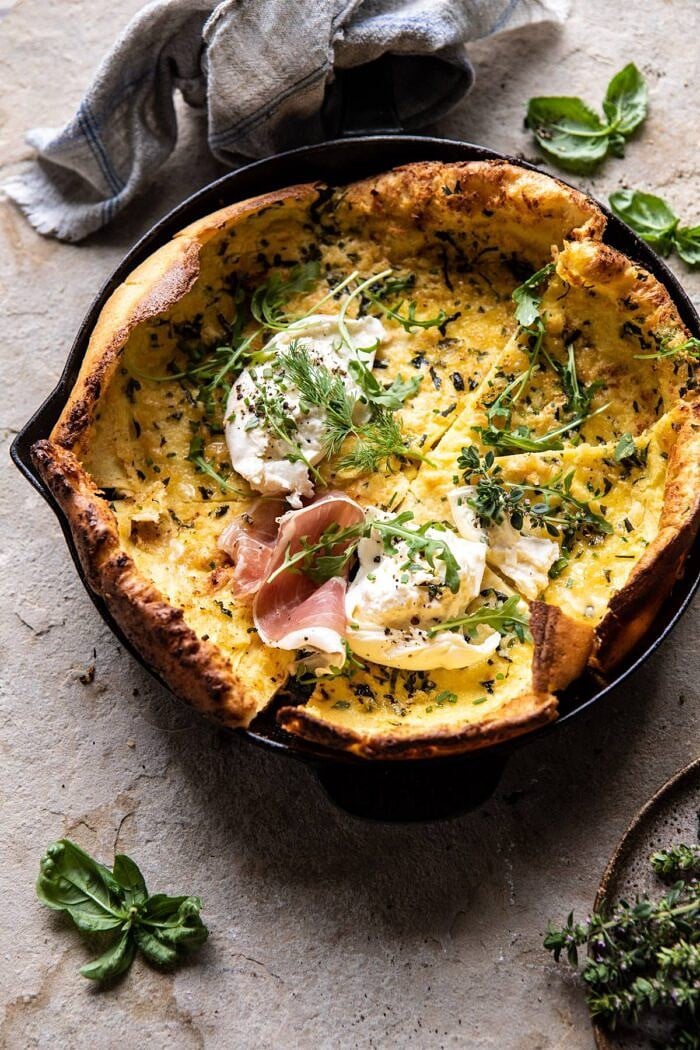 Savory Herb Butter Dutch Baby in skillet with 3 slices cut