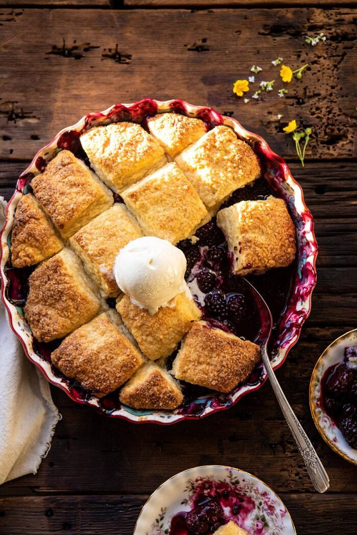 overhead photo of Blackberry Lavender Cobbler with ice cream on cobbler and spoon in baking dish 