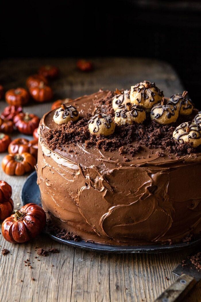 close up slide angled photo of Pumpkin Patch Chocolate Peanut Butter Cake with mini pumpkins in the background