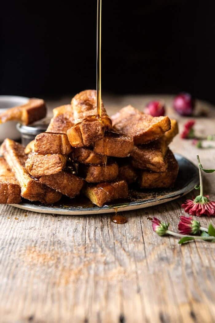 side angled photo of Cinnamon Sugar French Toast Sticks being drizzled with maple syrup 