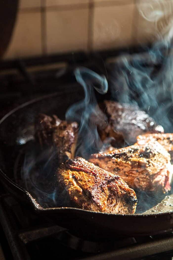 short ribs being seared on the stove in skillet