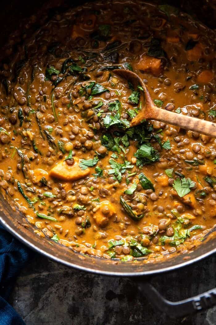 overhead photo of Sweet Potato Lentil Curry in pot with wooden spoon in curry