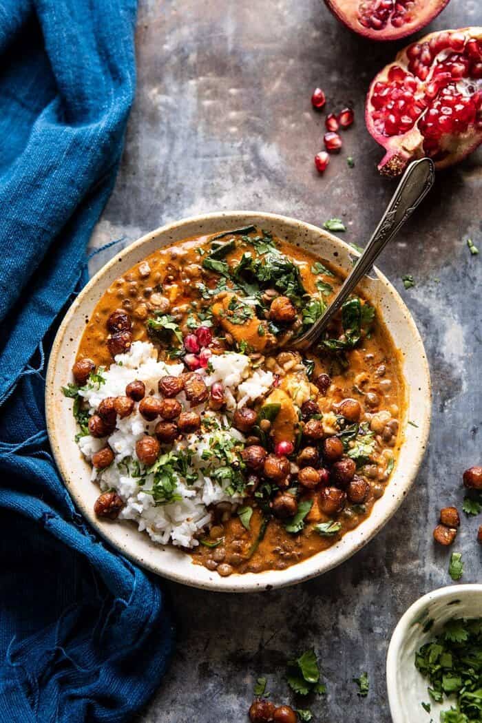 overhead photo of Sweet Potato Lentil Curry with Crispy Sesame Chickpeas and spoon in bowl scooping up the curry