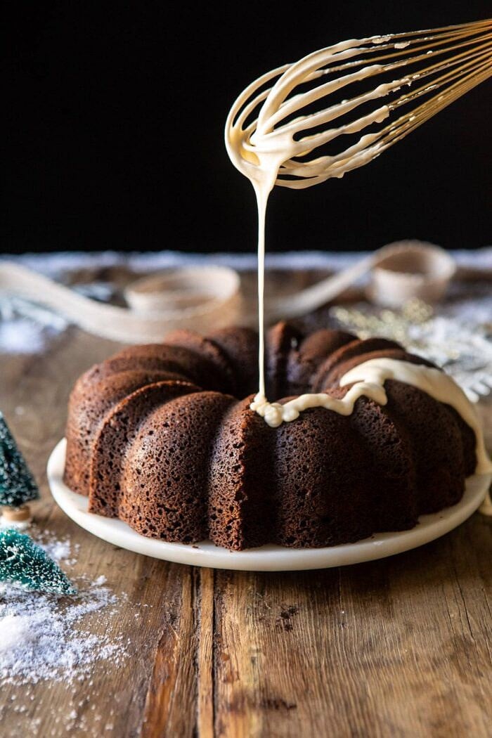side angled photo of Cream Cheese Swirled Chai Gingerbread Cake with the glaze being drizzled over the cake