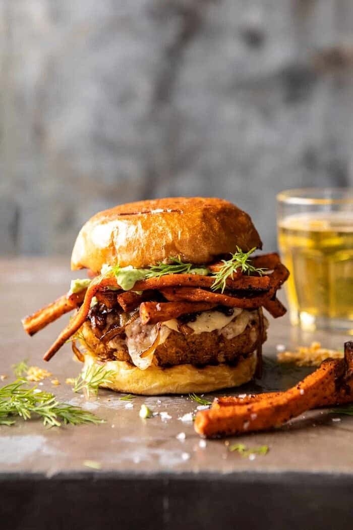 side angle photo of Crispy Quinoa Burgers Topped with Sweet Potato Fries and Beer Caramelized Onions 