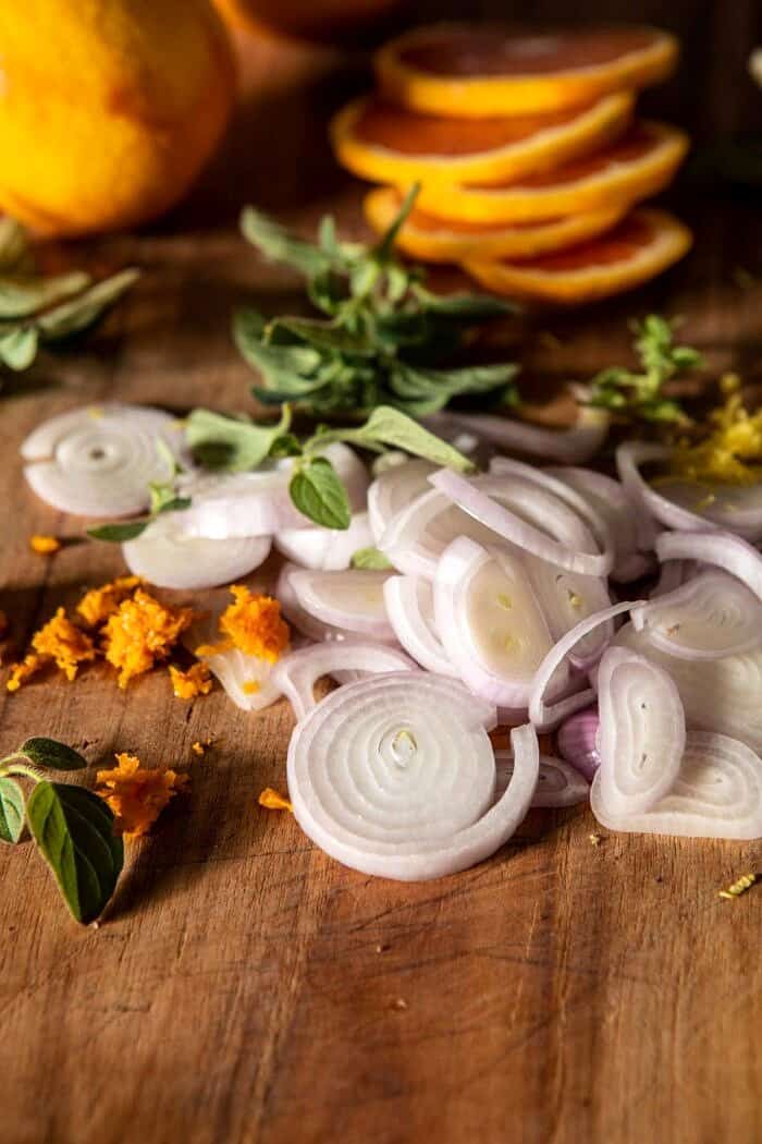 shallots and citrus on cutting board with herbs