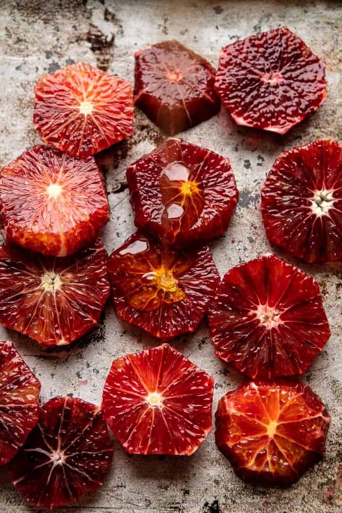raw blood oranges before roasting with honey being drizzled over oranges 