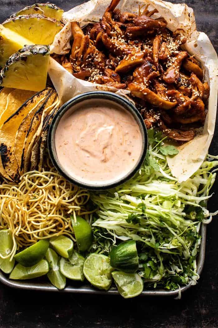 overhead photo of Slow Cooker Braised Hawaiian Pineapple Chicken with all of the toppings for the tacos