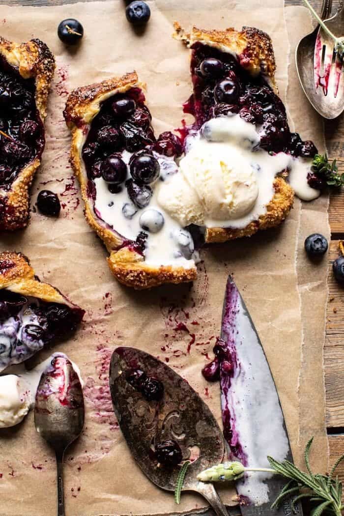 overhead photo of Bursting Blueberry Lemon Thyme Tarts cut in half with ice cream on top 
