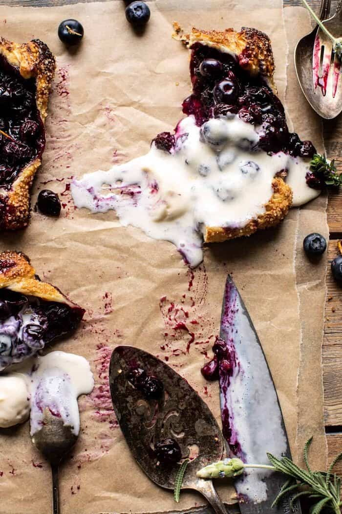 overhead photo of Bursting Blueberry Lemon Thyme Tart cut in half with ice cream melted on top