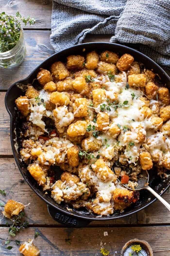 One Skillet French Onion Tater Tot Casserole with spoon in skillet and portions of casserole removed from skillet 