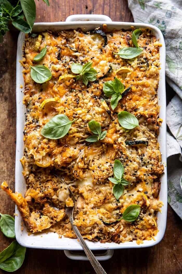 overhead photo of Cheesy Zucchini Chicken and Rice Bake with spoon in baking dish