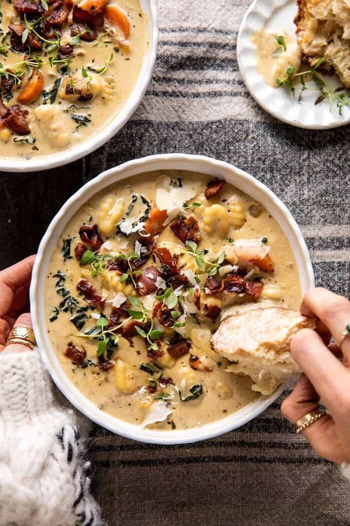 overhead photo of Creamy Gnocchi Soup with Rosemary Bacon and hands on bowl 