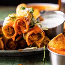 taquitos stacked with buffalo sauce dripping off