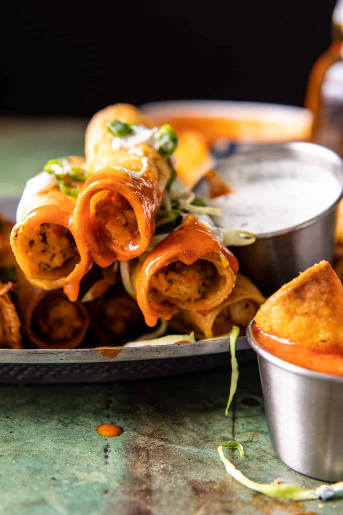 taquitos stack with buffalo sauce dripping off 