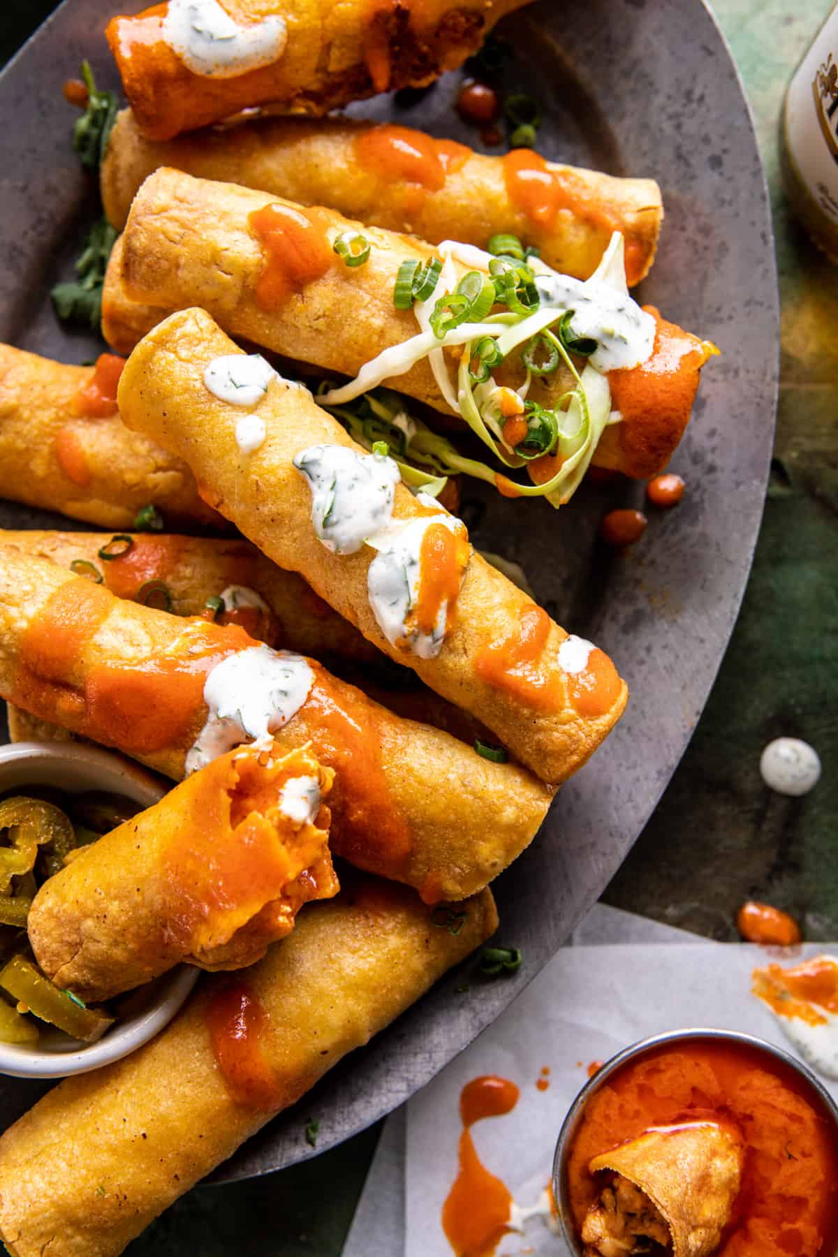 Taquitos on serving plate with sauce 