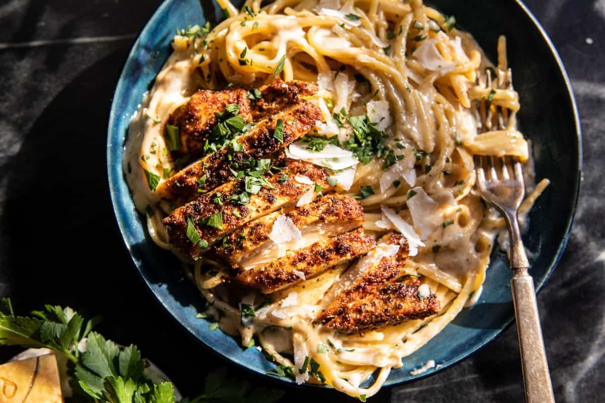 Lemon Pepper Cajun Chicken Fettuccine Alfredo in pasta bowl with fork and herbs 