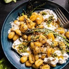 photo of gnocchi in bowl with burrata, asparagus, and for, basil on table
