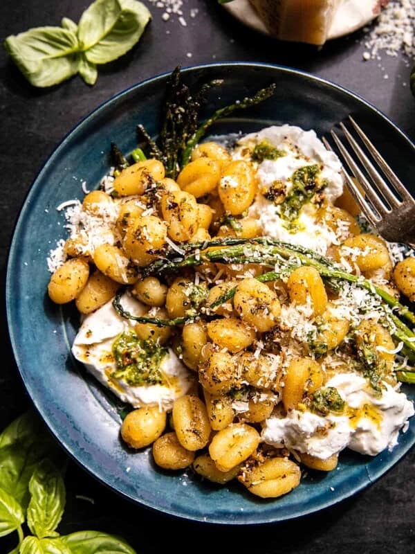 photo of gnocchi in bowl with burrata, asparagus, and for, basil on table