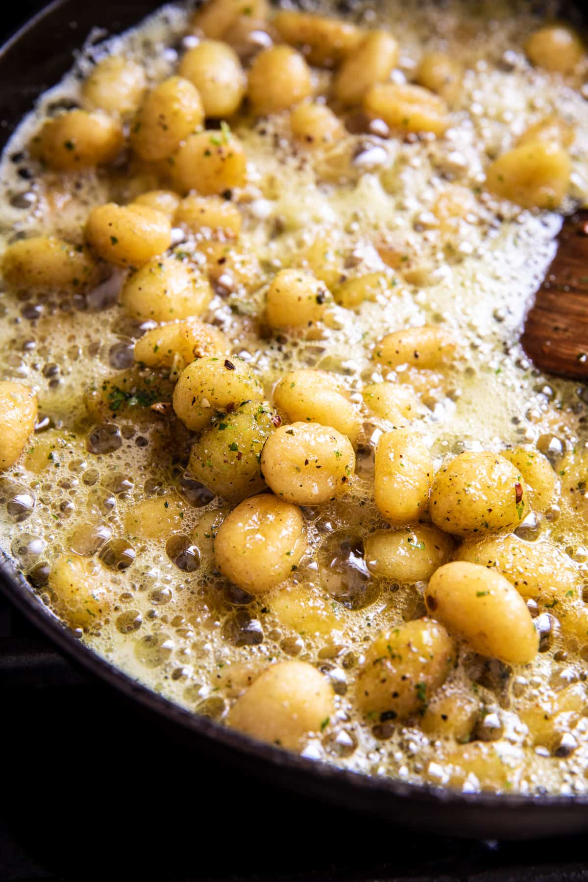 gnocchi cooking in skillet with butter and pesto 