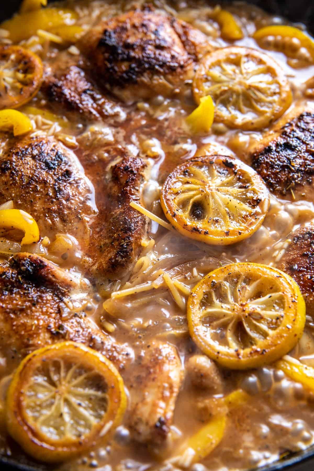 chicken, rice, and lemons in skillet cooking in broth 