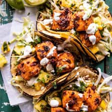 overhead photo of salmon tacos on serving board with toppings and limes
