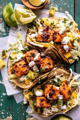 overhead photo of salmon tacos on serving board with toppings and limes