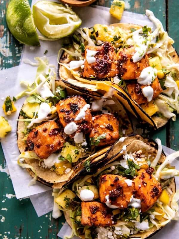 overhead photo of salmon tacos on serving board with toppings and limes