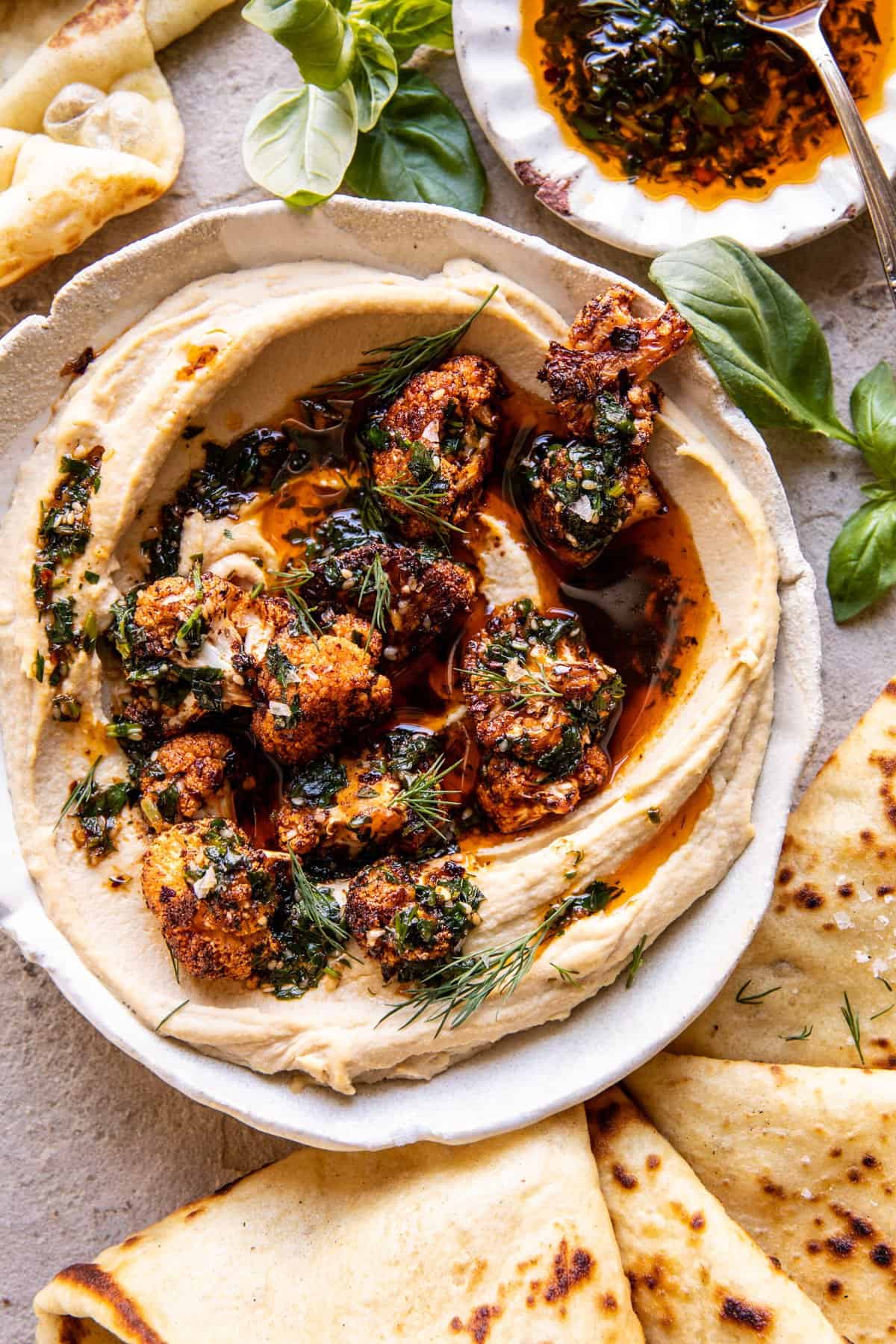 Crispy Roasted Cauliflower Hummus in bowl with chili oil and naan on the table 