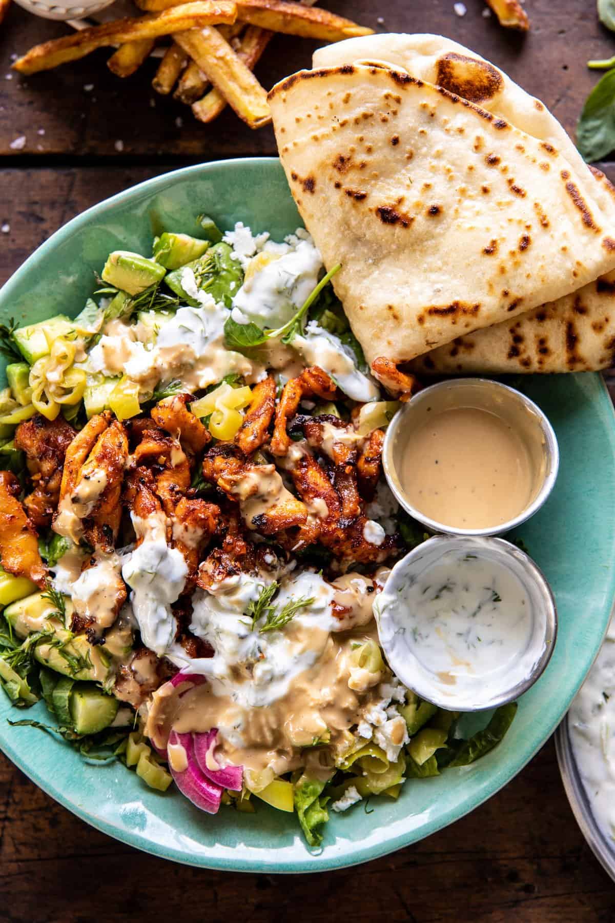 photo of Greek Chicken Tzatziki Bowl with fried on the table and naan on the side 