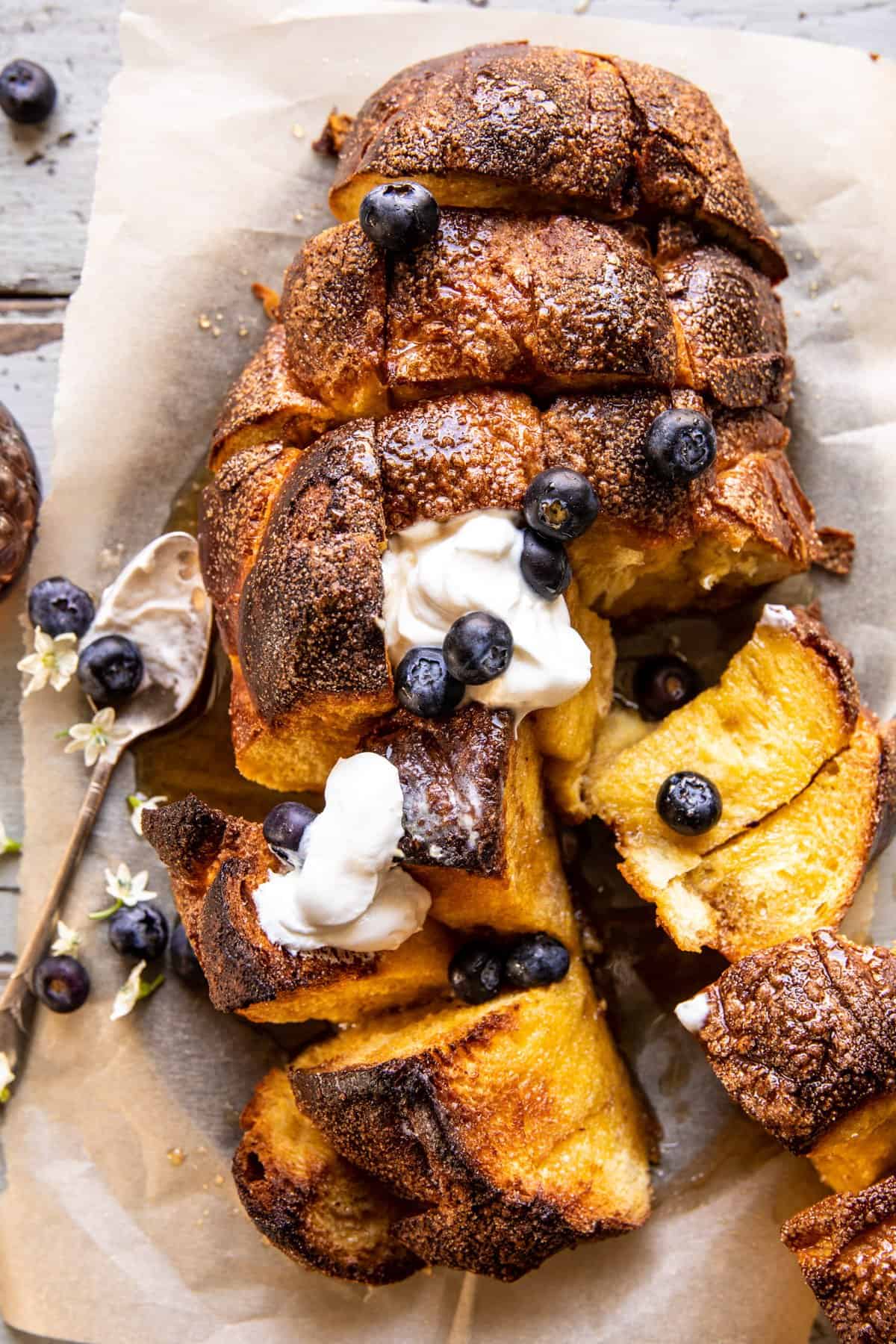 Pull Apart French Toast Bake broken in half with whipped cream and berries on top 