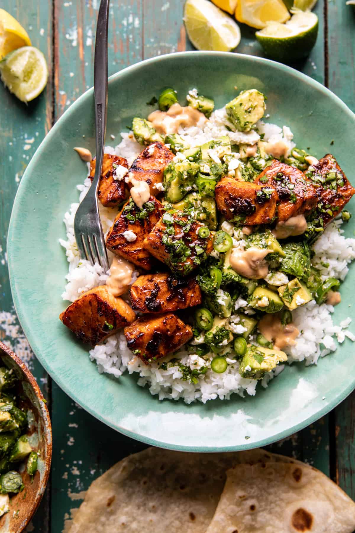 Spicy Chipotle Honey Salmon Bowls with limes on table and fork in bowl 